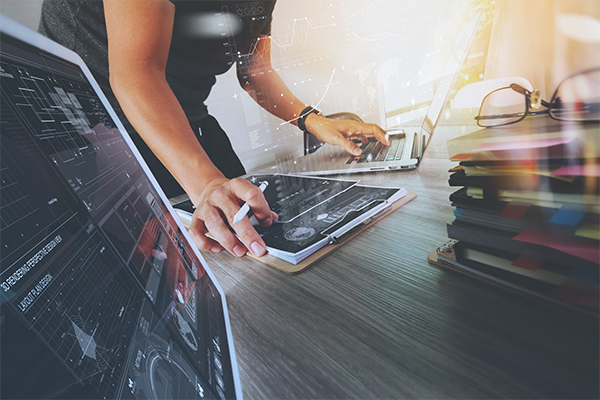 Professional working with network automation technology on laptop and tablet with data analytics overlay